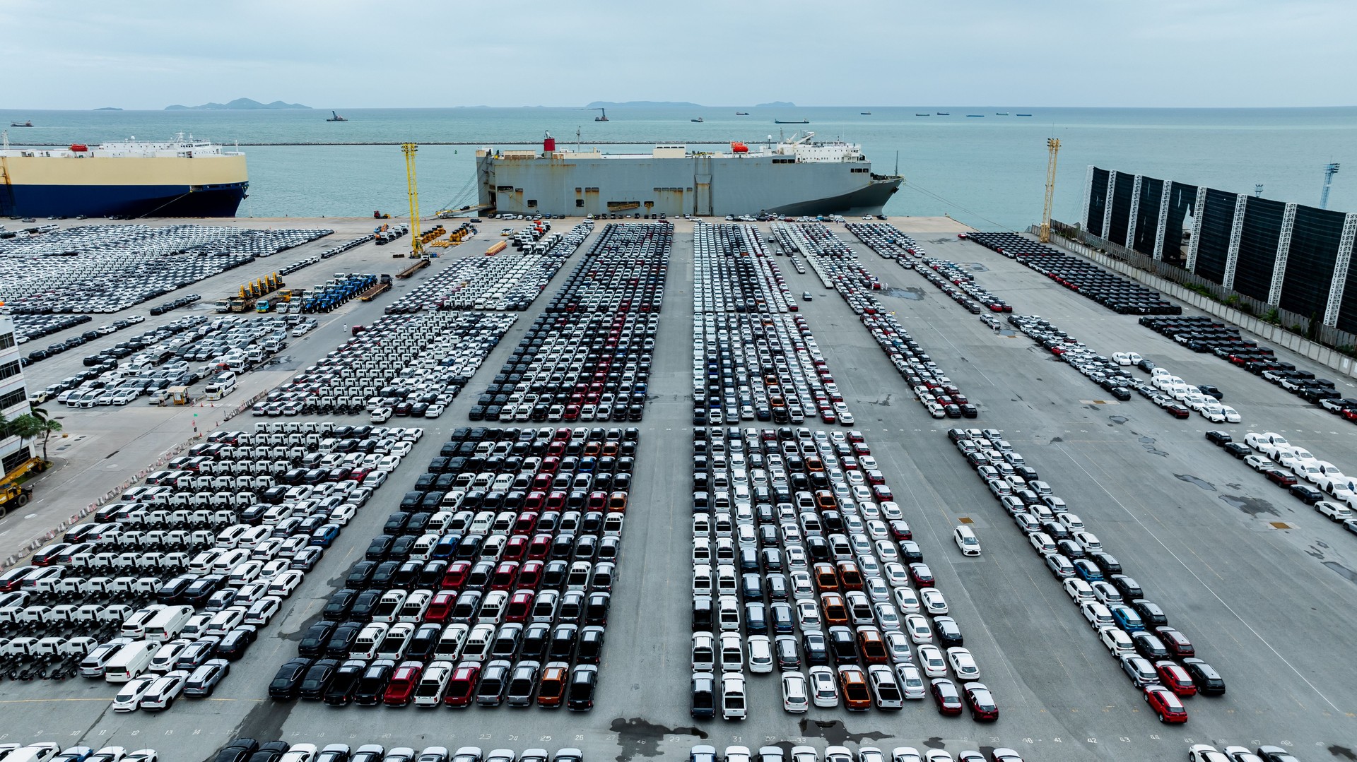 Aerial view new cars lined up in the factory and commercial port for import and export international by container ship transport  in open sea,